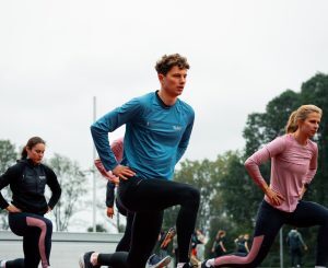 hardlopers op atletiekbaan tijdens warming up en loopscholing